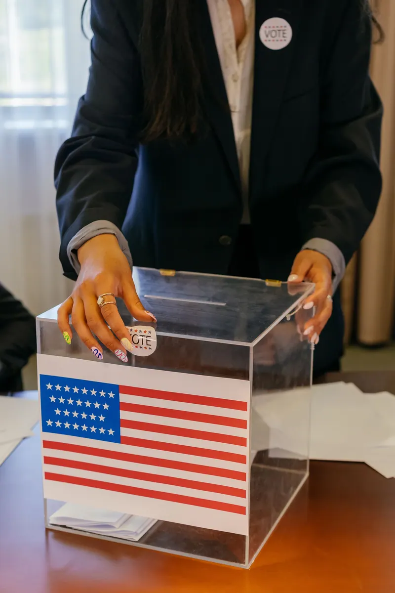 A person casting a vote in a US election using a transparent ballot box