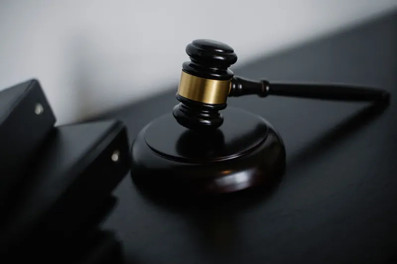 Wooden judge's gavel beside document folders on a desk