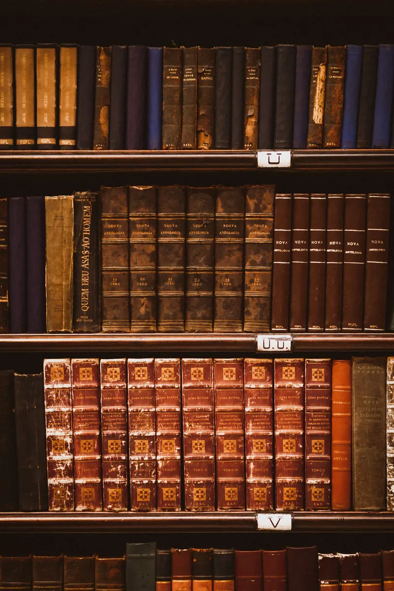 Rows of antique leather-bound books neatly arranged on wooden library shelves