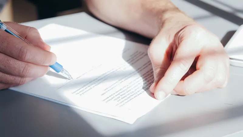 A person writes on a printed document